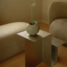 a vase with a flower in it sitting on a table next to a couch and chair