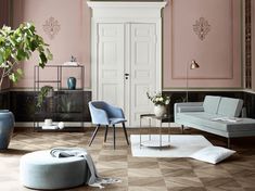 a living room with pink walls and white furniture in it, including a blue chair