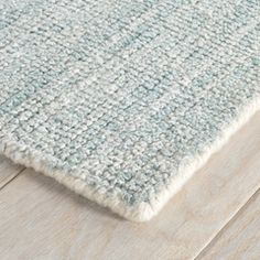 a close up view of a rug on a wooden floor with white and blue colors