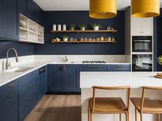 a kitchen with blue cabinets and white counter tops, yellow pendant lights over the island