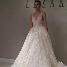 a woman standing in front of a white wall wearing a wedding dress