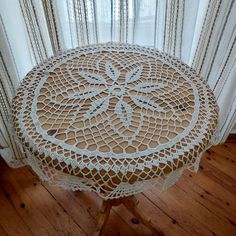 a doily covered table sitting on top of a wooden floor next to a window