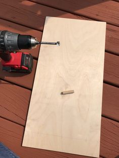 a drill and screwdriver sitting on top of a piece of plywood plank