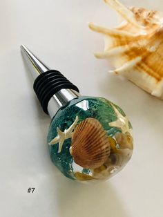 a bottle stopper sitting on top of a table next to a sea shell