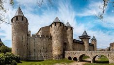 an old castle with two towers and a bridge in the foreground, on a sunny day