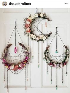 two wreaths hanging on the wall with flowers and beads attached to them, one has a pink stone