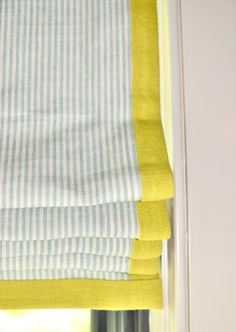 a yellow and blue striped roman blind in a window