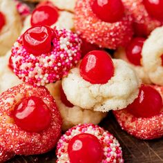 red and white cookies with sprinkles are arranged on a wooden table top