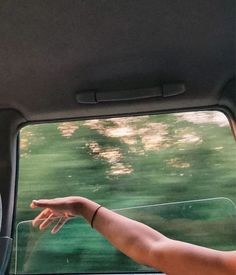 a person's hand reaching out the window of a car with trees in the background