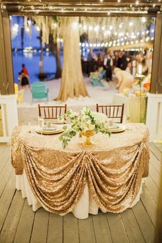 the table is set with gold cloths and white flowers