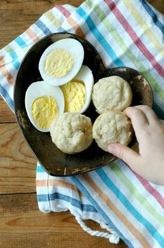 a person is holding an egg and some biscuits on a plate next to a towel