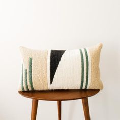 a black and white pillow sitting on top of a wooden table