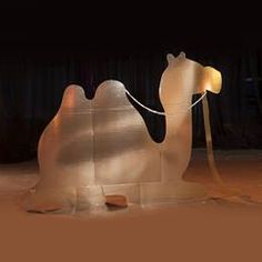 a glass sculpture of a camel in the middle of a stage with curtains behind it