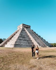 two people standing in front of an ancient pyramid