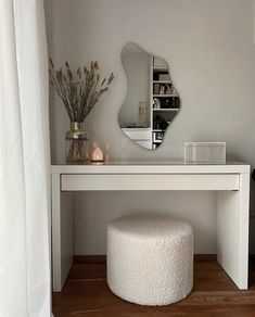 a white vanity table with a mirror above it and a stool in front of it