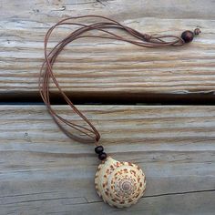 a necklace with a seashell on it is hanging from a wooden planked surface