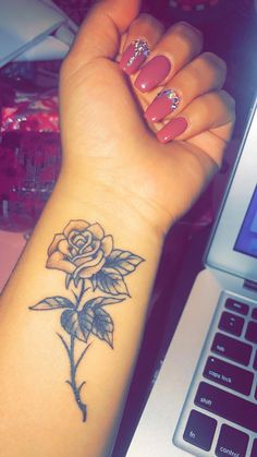 a woman's arm with a rose tattoo on it