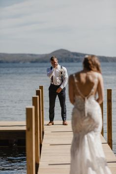 a bride and groom standing on a dock by the water