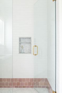 a bathroom with a glass shower door and pink tile