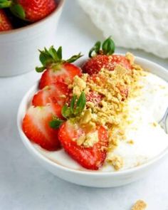 two bowls filled with yogurt and strawberries on top of a white table