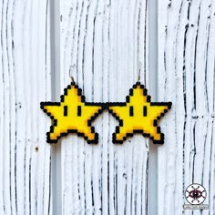 two yellow and black pixelated stars hanging on a white wooden fence with the word'star wars'written across them