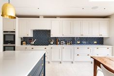 a large kitchen with white cabinets and blue backsplash tiles on the countertops