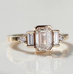 an engagement ring with three baguets on the side and two diamonds in the middle