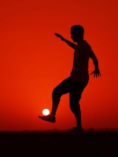 the silhouette of a man throwing a frisbee in front of an orange sky