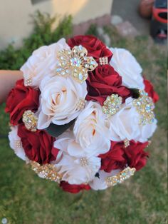 a bridal bouquet with red and white roses, brooches and diapers