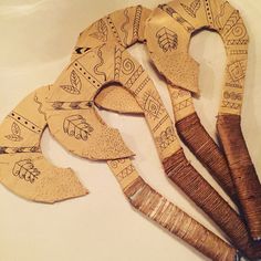 four wooden utensils with designs on them sitting on a white counter top next to each other