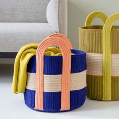 three colorful baskets sitting next to each other on the floor in front of a couch