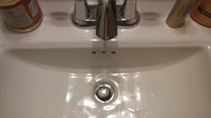 a white sink sitting under a faucet next to a counter top with bottles on it