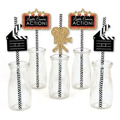 some glass vases with black and white striped straws next to each other in front of a sign that says action