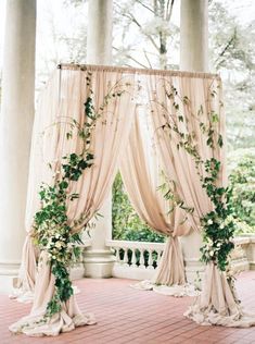 an outdoor ceremony setup with drapes and greenery