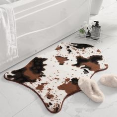 a brown and white cow hide rug next to a bathtub