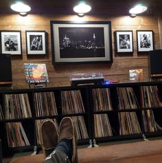 a man's feet resting on a book shelf in front of a record collection