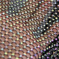 a woman's legs covered in sequins and black mesh material with her hand under the net