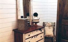 an old dresser and mirror in a room with white walls, wood floors and wooden doors