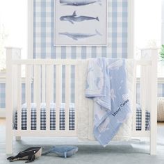 a baby's room with blue and white wallpaper, a crib bedding set and shoes on the floor