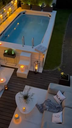 an aerial view of a pool at night, with candles lit up around the lounge area