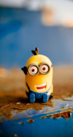 a small yellow toy sitting on top of a wooden table next to a blue wall