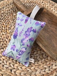 a purple flowered pillow sitting on top of a basket next to a wooden paddle