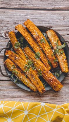 grilled carrots on a plate with herbs and seasoning next to a yellow napkin