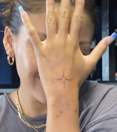 a woman holding her hand up to her face with a cross tattoo on the wrist