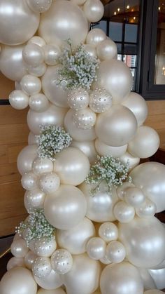 white balloons and baby's breath flowers are arranged in the shape of a tower