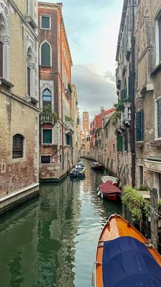 boats are parked along the side of a narrow canal in venice, italy on a cloudy day