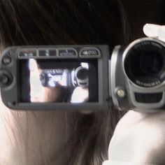 a woman holding up a camera to take a photo with her reflection in the mirror