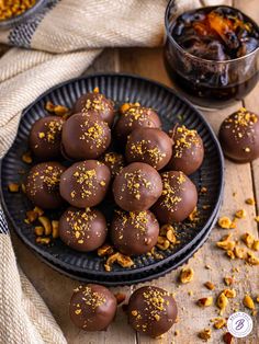 a plate full of chocolate truffles with nuts on the table next to it