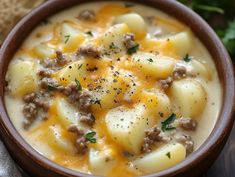 a brown bowl filled with potatoes and meat in gravy on top of a table