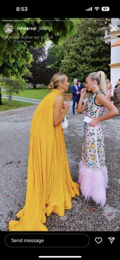 two women standing next to each other in front of trees